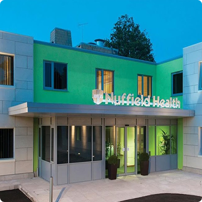 The entrance of the hospital showing modern green walls with Nuffield Health written in big letters above the door