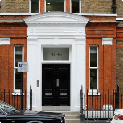 Entrance to a private medical clinic in a red-brick building with black double doors and white stone detailing